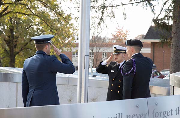 Three military personnel saluting each other